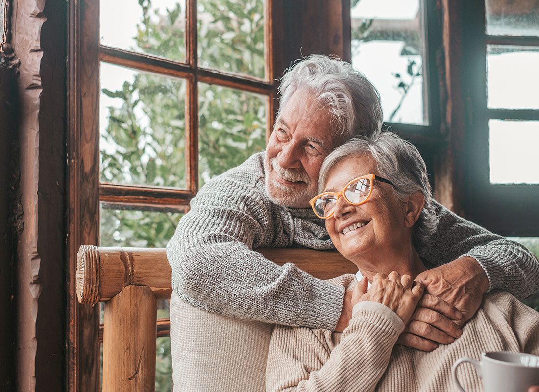 Medicare - Portrait of a Cheerful Senior Couple Spending Time Together Hugging and Drinking Coffee in Their Home in the Morning